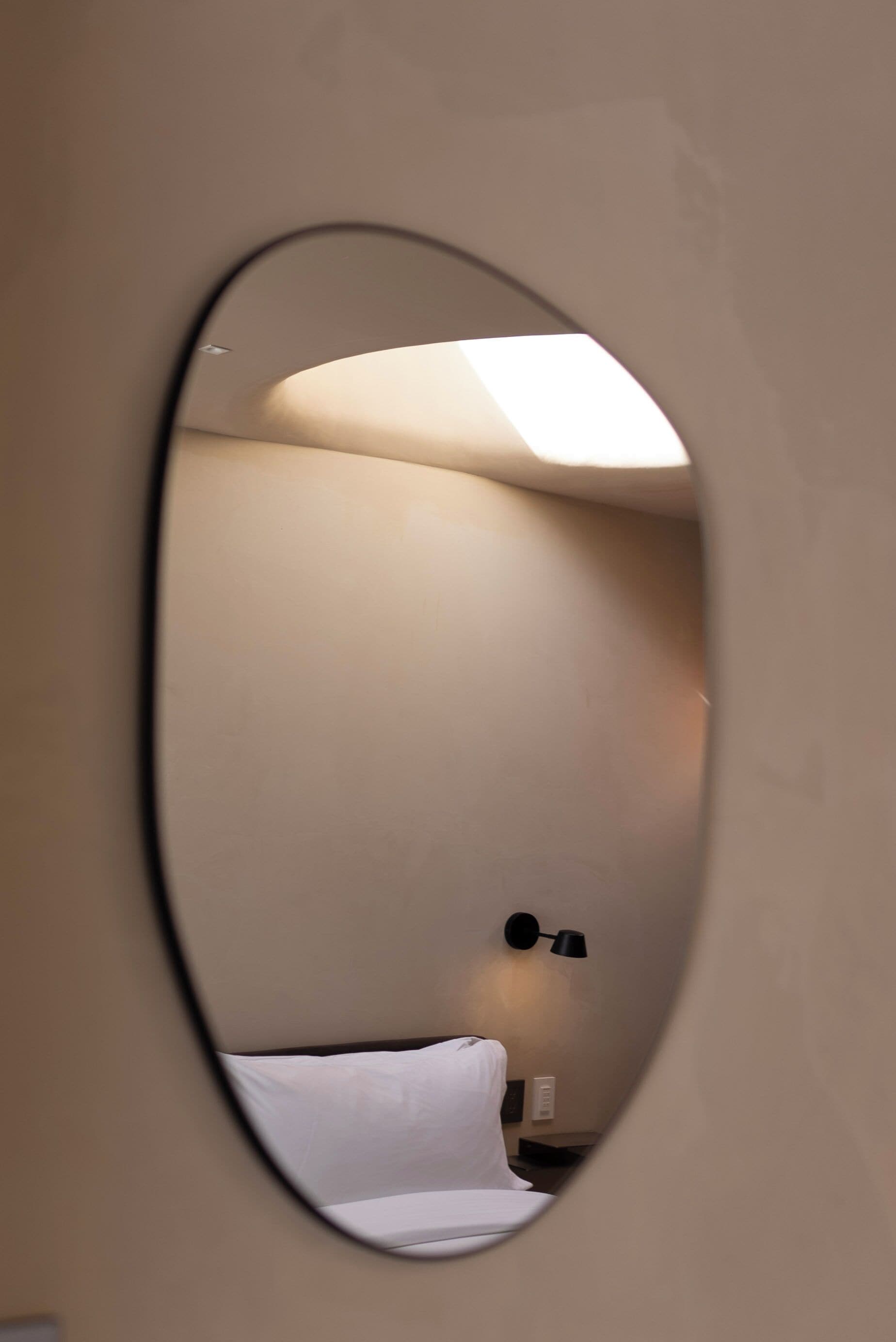 Une pièce avec un lit, une lampe fixée au mur et un luminaire au plafond.