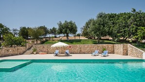 Une piscine avec des chaises longues et un mur en pierre.
