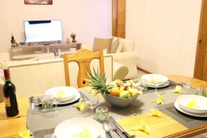 A dining table set with plates, cutlery, glasses, and a bowl of fruit. A bottle of wine is on the table. - Mountain View Suite with mountain panoramic view (Trou d'Eau Douce)