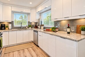 A modern kitchen with white cabinets, a granite countertop, and a built-in dishwasher. - Singer Island 3br/2ba Beach, Snorkel gear & Bikes (West Palm Beach)