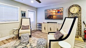 A modern living room with a ceiling fan, two armchairs, a TV, and a decorative clock. - Singer Island 3br/2ba Beach, Snorkel gear & Bikes (West Palm Beach)