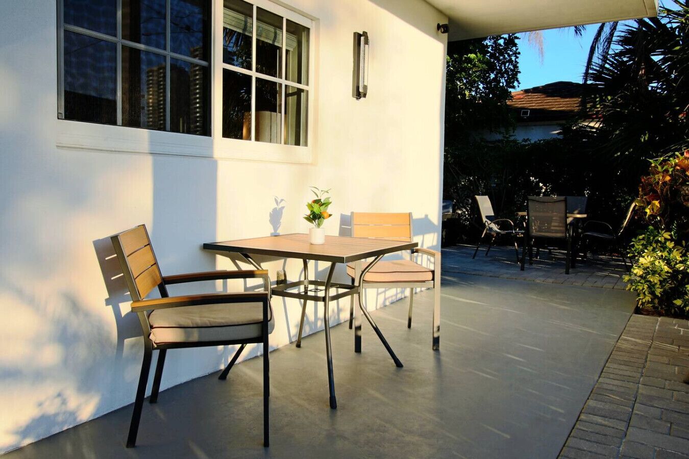 Un patio con mesa y sillas, una planta en maceta y vistas a una zona residencial.