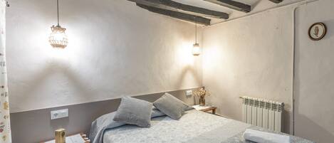 Una camera da letto con un letto, un comodino, una lampada e un termosifone.