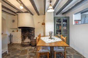 A rustic interior with a stone fireplace, wooden table, and chairs. - Cargol de Mas Violella: rural charm in natural park, direct garden access, pool & wifi (Sant Joan Les Fonts)