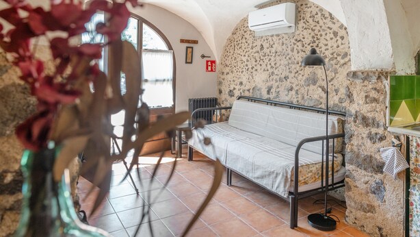 Una habitación con una cama, un radiador, una ventana y aire acondicionado instalado en la pared.