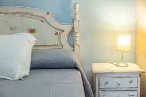 A bed with a white headboard and a bedside table with a lamp.