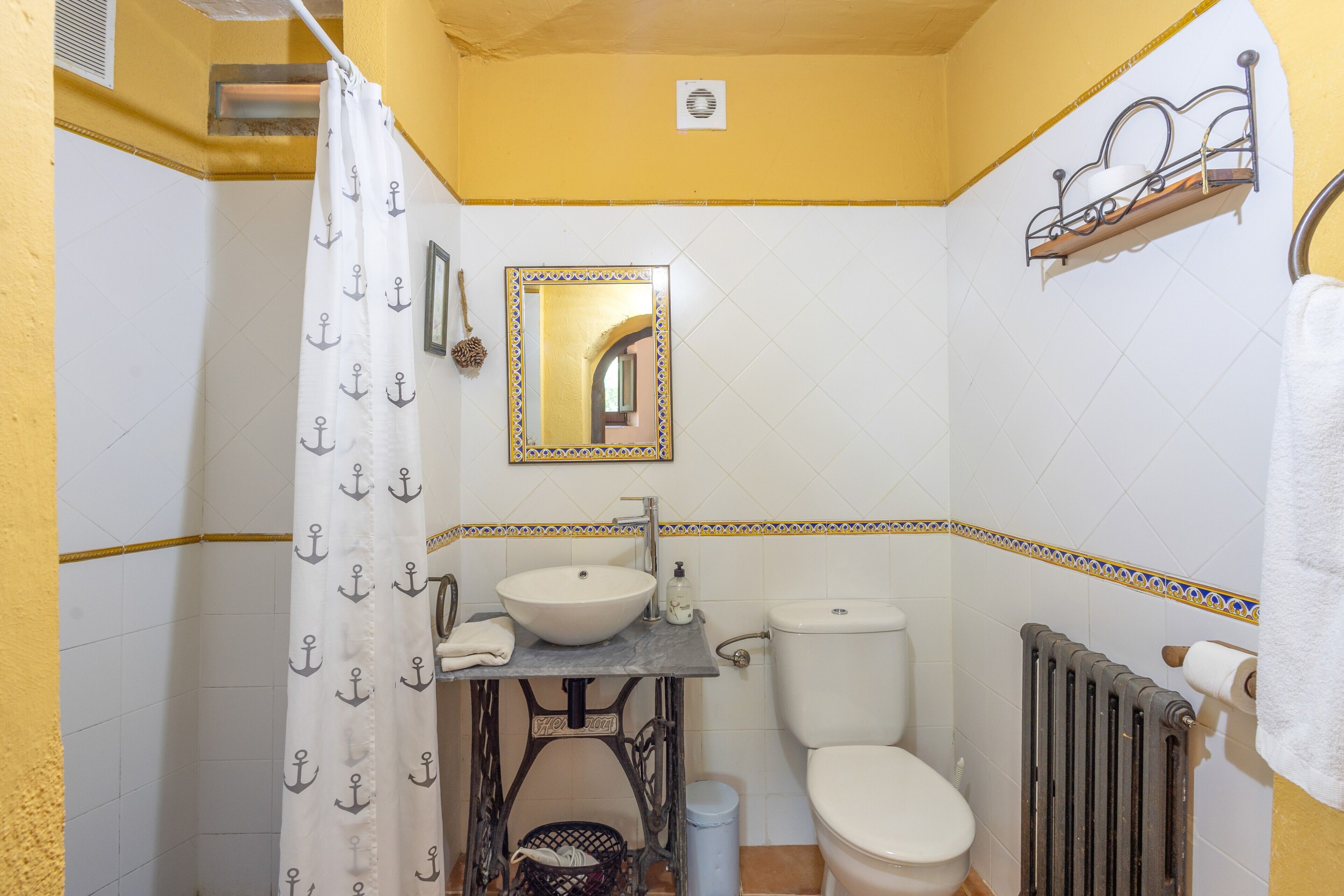 A bathroom with a white sink, a toilet, and a shower curtain with anchor patterns.