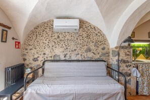 Ein Zimmer mit Bett, Klimaanlage, Heizkörper und einer Küchenzeile mit Spüle und Geschirr.