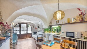 Cocina compacta con comedor, cama y vista a través de un arco.
