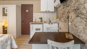 Una cucina compatta con un tavolo di legno, un lavello bianco e un muro in pietra.