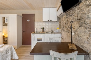 Eine kleine Küche mit Holztisch, weißem Spülbecken und Wand aus Stein.
