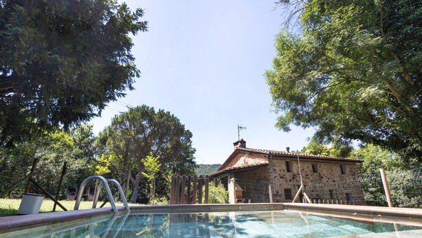 Una piscina con un edificio in pietra sullo sfondo.