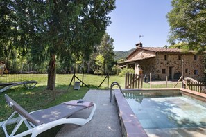 A pool area with lounge chairs, a stone building, and a fenced garden. - Cabana at Mas Violella: Charm, Views, and Natural Light. Air Conditioning & Wi-Fi (Sant Joan les Fonts)