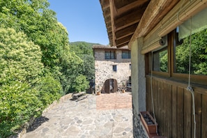 A stone courtyard with a wooden bench, a rustic stone building, and a wooden pergola. - Cabana at Mas Violella: Charm, Views, and Natural Light. Air Conditioning & Wi-Fi (Sant Joan les Fonts)