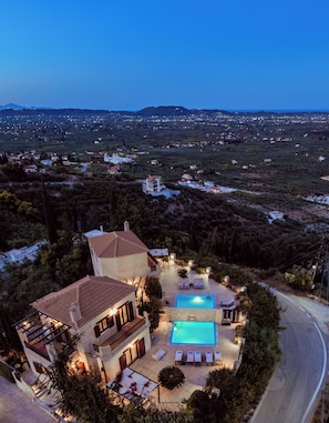 Eine Villa mit Swimmingpool, mehreren Lounges und Blick auf die umliegende Landschaft.