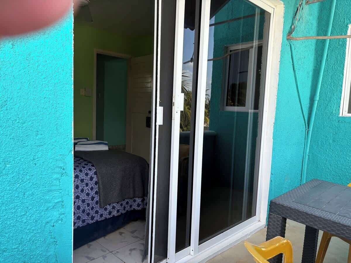 Une chambre avec un lit, une porte-fenêtre coulissante donnant sur un espace extérieur et une petite table.
