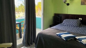 A room with a bed, a chair, a table, and a view of a pool. - Delightful Beach Time in Chelem! (Chelem)