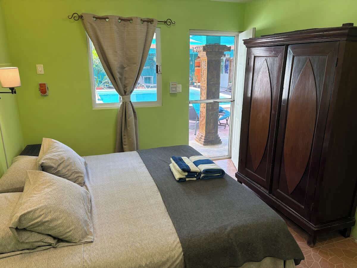 Une chambre à coucher avec un lit, une armoire, une fenêtre avec des rideaux et une vue sur l’extérieur.