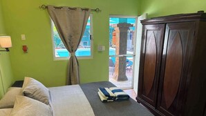 Ein Schlafzimmer mit Bett, Kleiderschrank, einem Fenster mit Vorhängen und Blick nach draußen.