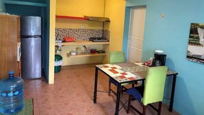 Eine kompakte Küche mit Kühlschrank, Wasserspender und gefliestem Fliesenspiegel.