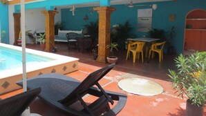 Ein Poolbereich mit Liegestühlen, einem Tisch und Stühlen.
