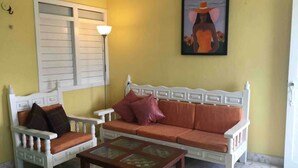 A room with a white sofa and a white armchair with cushions, a wooden coffee table, and a painting on the wall. - Comfortable Beach Living in a Mexican village! (Chelem)