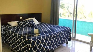 A bedroom with a bed, a headboard, a window with curtains, and a view of greenery outside. - Comfortable Beach Living in a Mexican village! (Chelem)