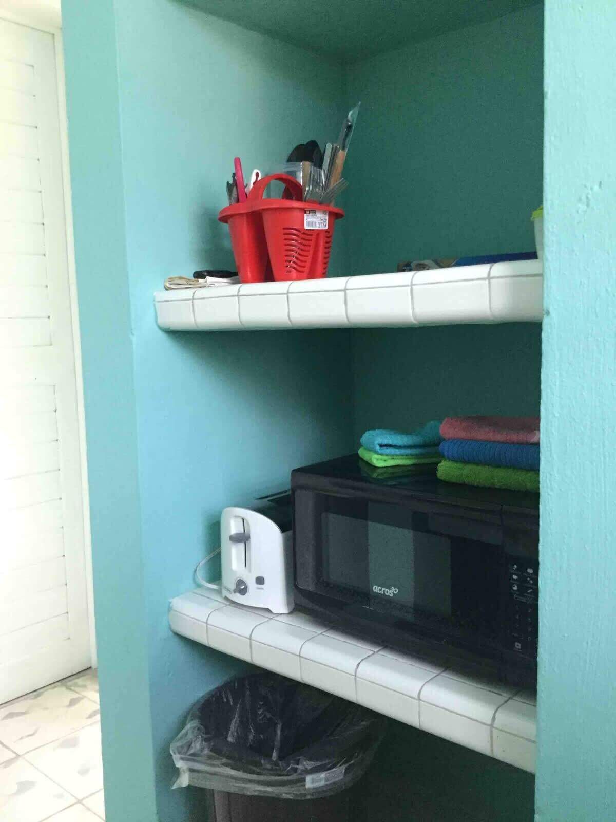 Een kitchenette voorzien van een magnetron, broodrooster en een afvalbak.