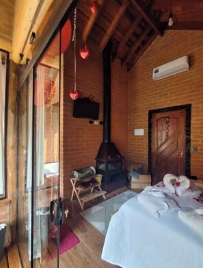 Une pièce chaleureuse avec un lit, un plafond en bois, un mur en briques et une cheminée.