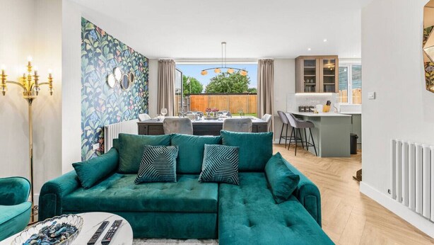 Una sala moderna con un sofá azul verdoso, un comedor y una cocina.