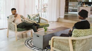 A modern lounge area with wicker furniture, a coffee table, and a view of the outdoor seating area. - Matatane Wilderness Camp (Babanango Game Reserve)