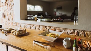 A dining table with food items and condiments, set against a stone wall with a window in the background. - Matatane Wilderness Camp (Babanango Game Reserve)