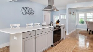 A modern kitchen with a central island, stainless steel appliances, and a decorative wall piece. - Tilghman | Pool | Private Dock | Pet Friendly (Tilghman)