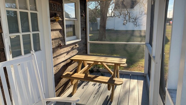 A wooden deck with a picnic table and a white chair. - Cozy cottage (Chincoteague)