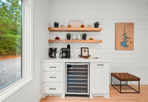 A modern kitchen with white cabinetry, wooden shelves, and a coffee station. - Creekside | Disc Golf | Movie Room | Hot Tub (Broken Bow)