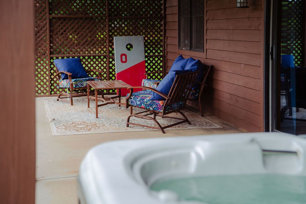 Un patio cubierto con dos mecedoras, una mesita y un jacuzzi.