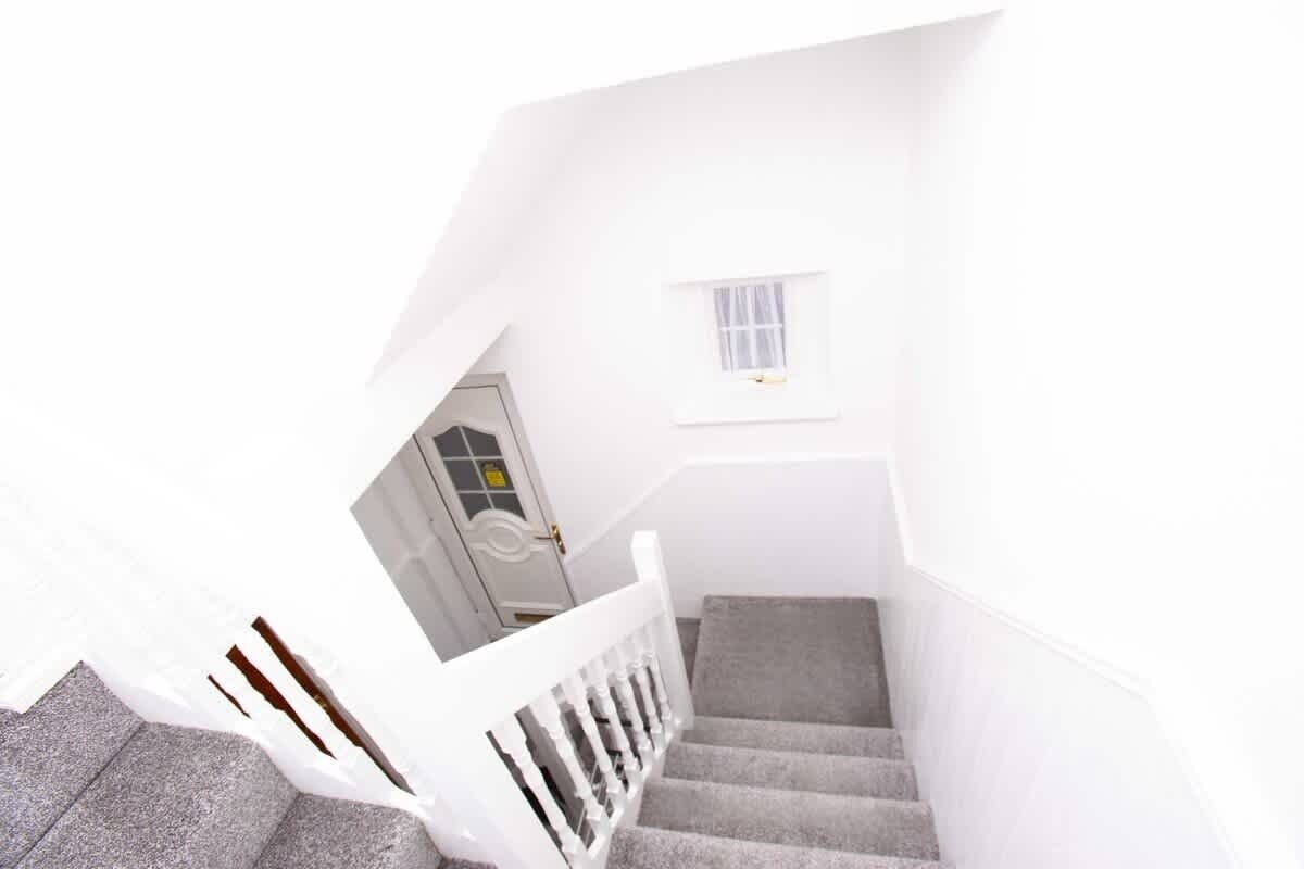 A white interior with a staircase leading to a door.