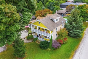 A two-story house with a balcony, surrounded by lush greenery and trees. - THE VICTORIA: Grand Appartement
Located in the heart of Elora! (Elora)