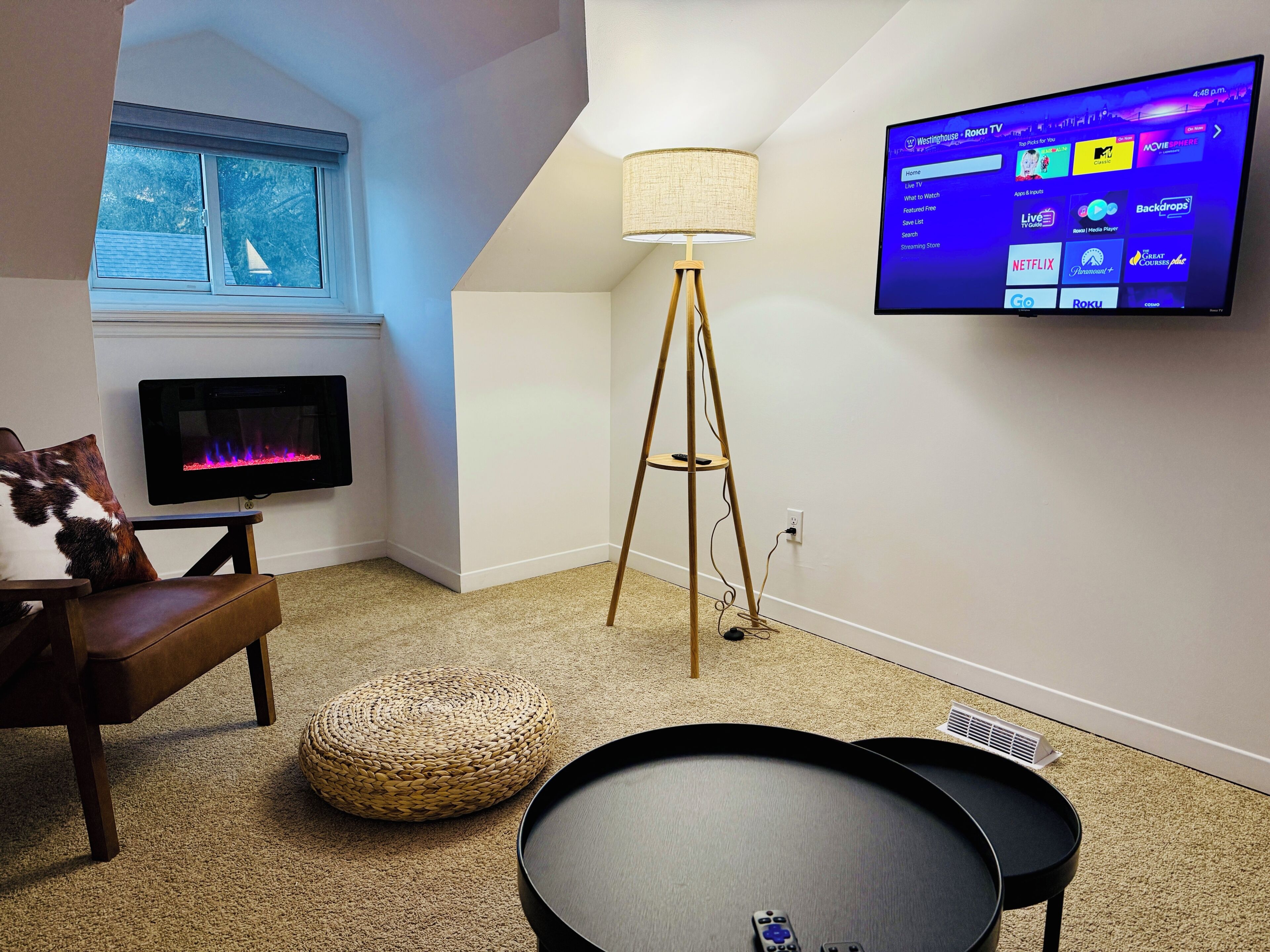 Sala de estar com televisão de tela plana, abajur, sofá e mesa redonda.
