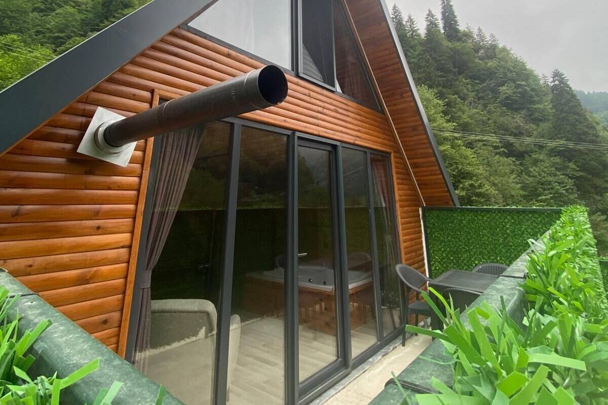 Une cabane en rondins moderne, dotée d’un toit en pente, de grandes fenêtres et d’une cheminée.