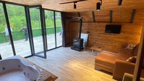Une pièce spacieuse avec un plancher en bois, un jacuzzi, un canapé et une télévision.