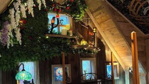 Une chambre confortable située dans les combles, avec un plafond en bois, un lit recouvert d’une courtepointe bleue et blanche, un lustre et des œuvres d’art accrochées au mur.