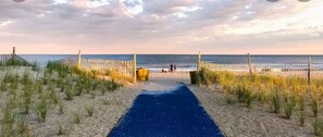 A beach pathway leading to the sea with a wooden fence and a blue mat. - Steps From the Beach Designer Space For 2 (Rockaway Beach)