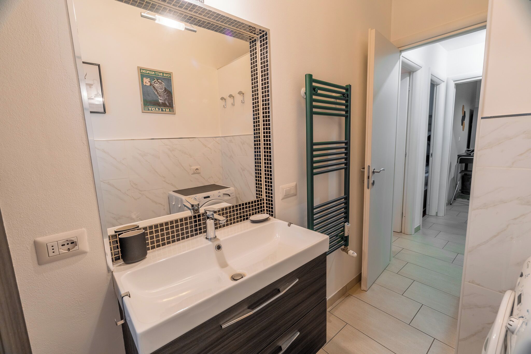 A bathroom with a white sink, a mirror, a towel rack, and a shower area.