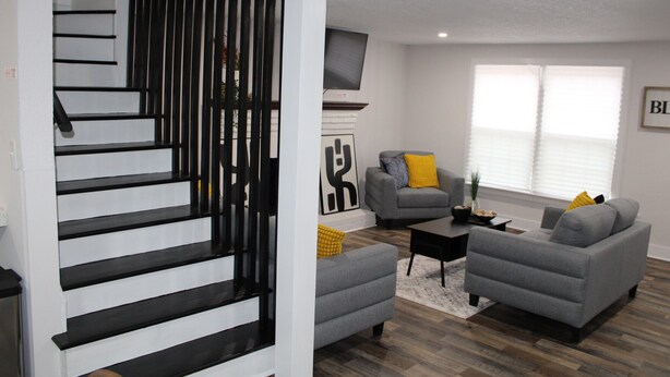 Ein modernes Wohnzimmer mit Treppe, grauen Sofas und minimalistischem Design.