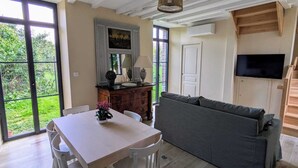 Un vaste espace de vie comprenant une table à manger, un canapé et un téléviseur fixé au mur.