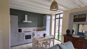 Une cuisine moderne avec des meubles blancs, une table à manger et un luminaire suspendu.