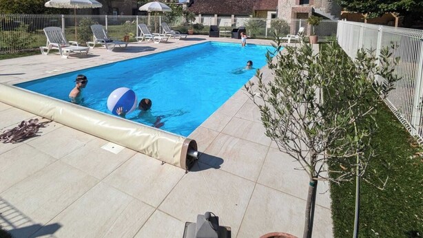 Une piscine avec des chaises longues et un petit bâtiment en arrière-plan.