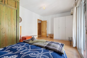 Un dormitorio con una cama, un armario de madera, una mesita y un guardarropa con puertas correderas.