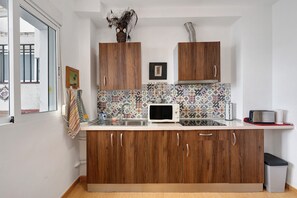 Een keuken met houten kastjes, een magnetron en een betegelde spatwand.